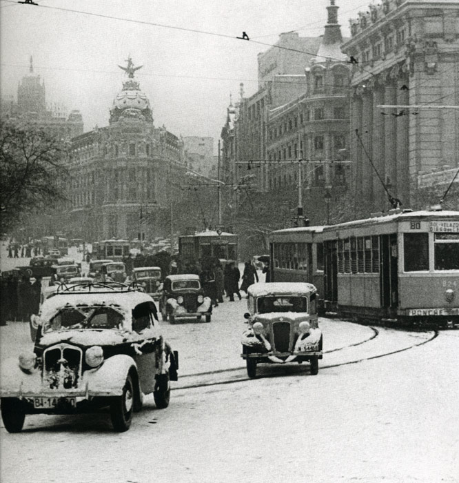 1945. Calle Alcal� junto a Cibeles. Bajo una fuerte nevada un intenso tr�fico de coches se desenvuelve junto a los tranv�as.