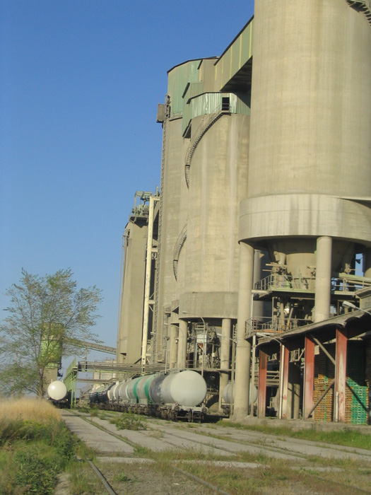Unos vagones cisternas, de cemento en polvo a granel, esperan bajo los inmensos silos de la cementera